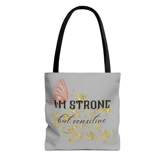 Strong but Sensitive Tote Bag with pink butterfly and gold glitter design on gray background and black handles